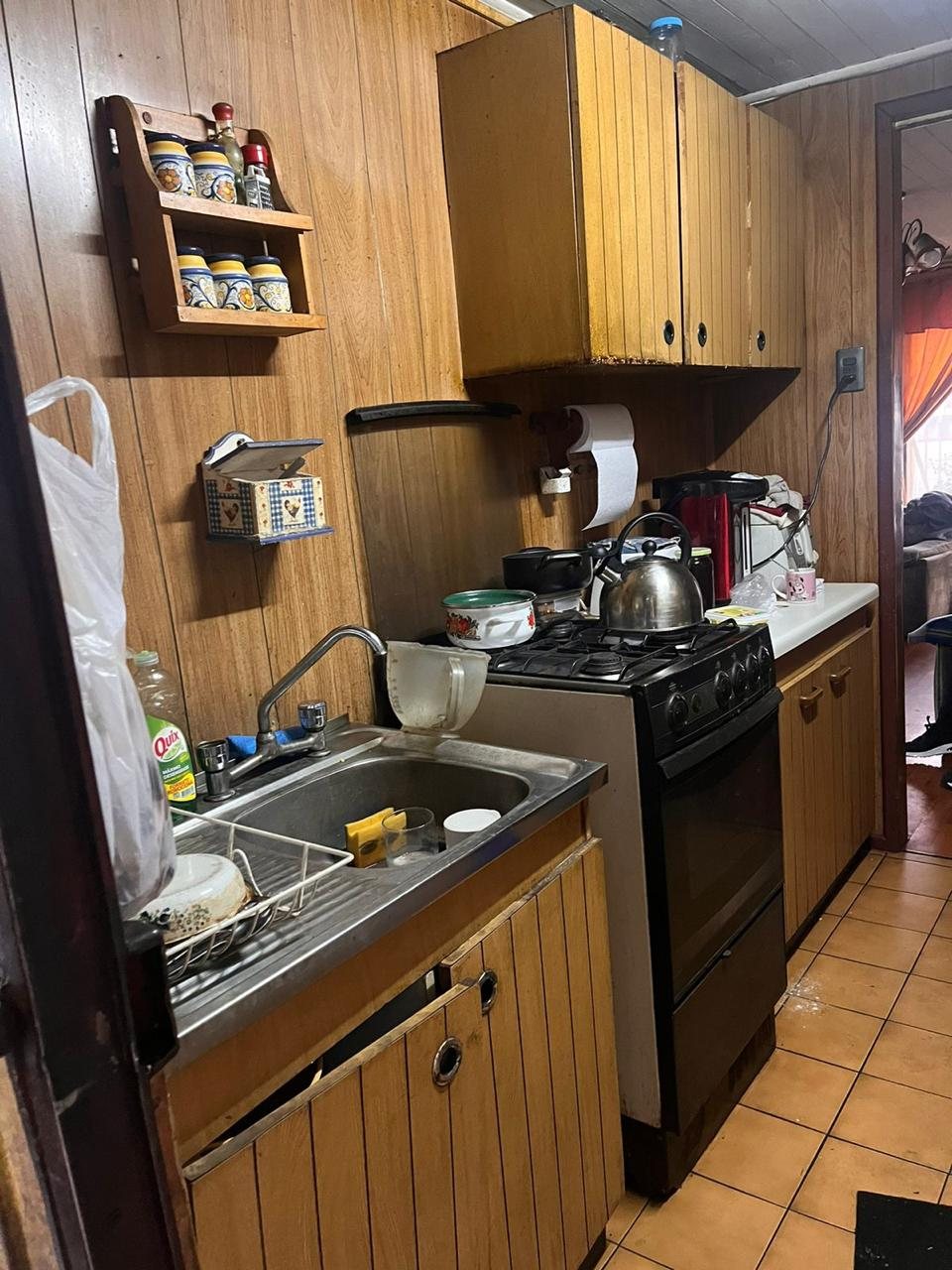 Antes: cocina antigua con muebles de madera barnizada y paredes de tablas