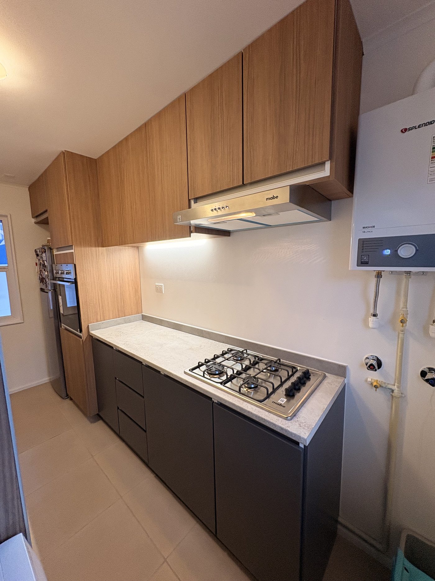 Cocina con muebles altos de roble, campana, iluminación LED y base grafito
